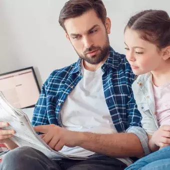 Papá explicando una noticia del periódico a su hija