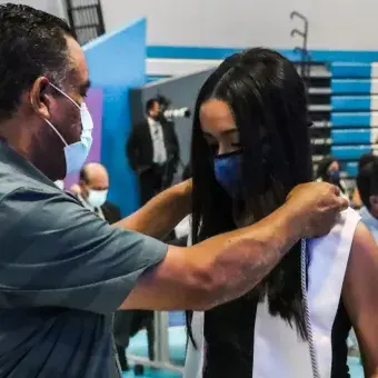Papá colocando estola a su hija graduada