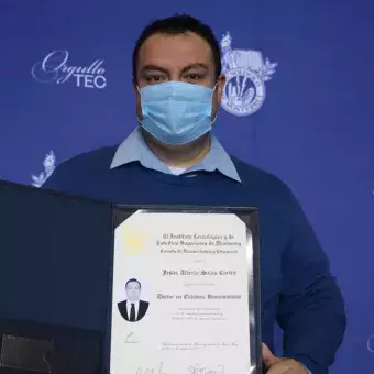 Un egresado de doctorado posó para la foto con su título.