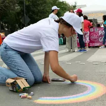 Una adolescente dibuja un arcoíris en el suelo.