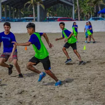 Grupo de alumnos jugando fútbol en la playa