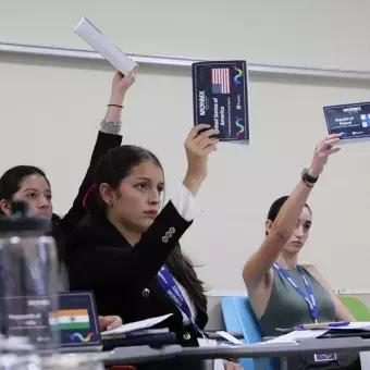 Estudiantes levantan la mano para participar