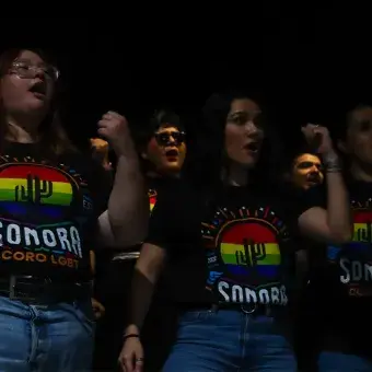 Tres personas cantadno como parte de un coro. 