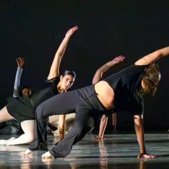 Bailarinas del Tec de Monterrey campus Laguna se presentan sobre fondo negro y realizan figuras en el suelo del Teatro Isauro Martínez
