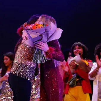 Estudiante recibiendo flores de profesora