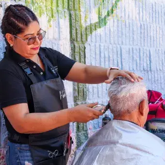 Estilista cortando el cabello de un hombre mayor. 