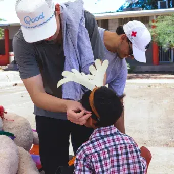Joven voluntario acomodando diadema con decoración en cabeza de niño.