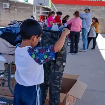 Niño sosteniendo par de pantalones. 
