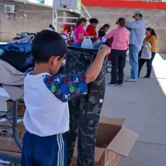 Niño sosteniendo par de pantalones. 