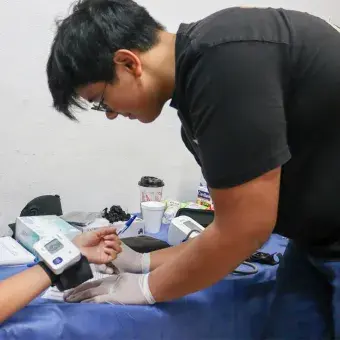 Joven voluntario tomando la presión arterial de una niña. 