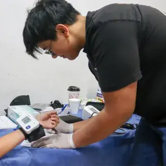 Joven voluntario tomando la presión arterial de una niña. 