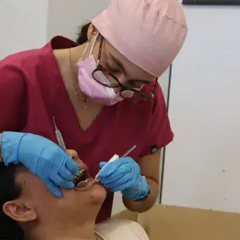 Dentista revisando boca de paciente. 