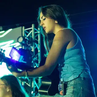 Alumna tocando la guitarra en concierto.