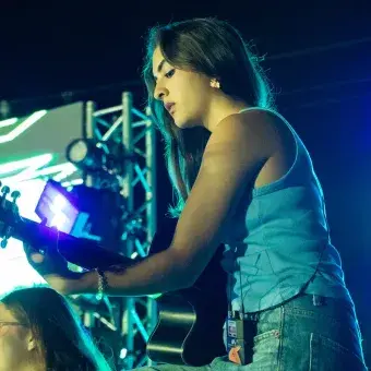 Alumna tocando la guitarra en concierto.