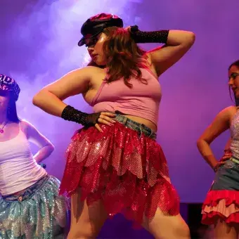 Tres jóvenes adolescentes en escenario con ropa al estilo de la moda de los 2000.