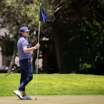 Participante del EXATEC Blue Open sostiene la bandera en el green del Club de Golf Pachuca, sede del torneo con causa del Tec de Monterrey, campus Hidalgo.