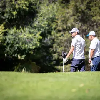 Dos participantes caminan entre los árboles del campo de golf durante el EXATEC Blue Open en el Tec campus Hidalgo.