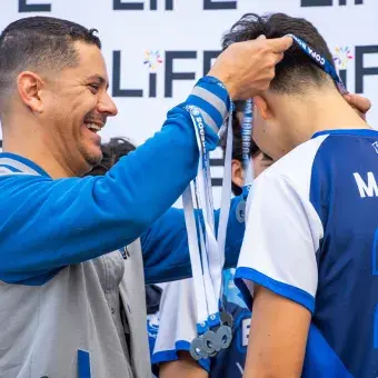 Un entrenador colocando una medalla sobre la cabeza de un jugador. 