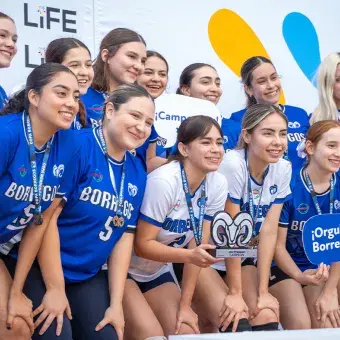 Equipo de voleibol femenil posando con un trofeo. 