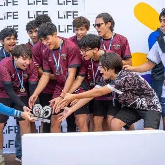 Equipo de fútbol varonil tomando un trofeo de las manos de un entrenador.. 