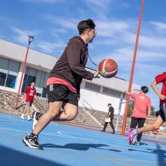 Alumnos de preparatoria jugando básquetbol. 